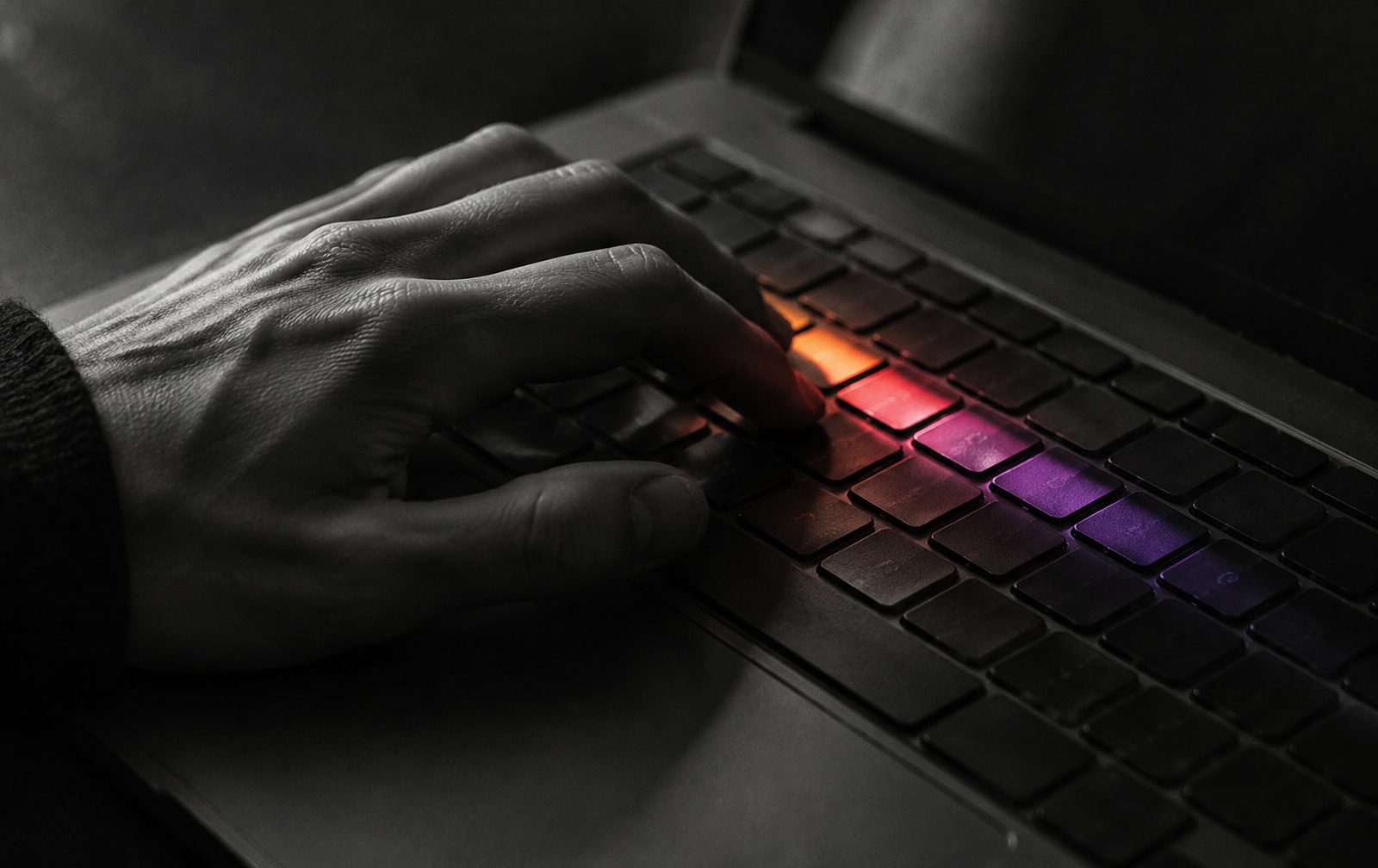 Main posée sur un clavier éclairé dans la pénombre